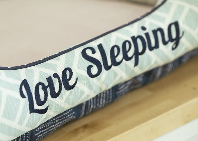 Bolster bed embroidered with the phrase Love Sleeping