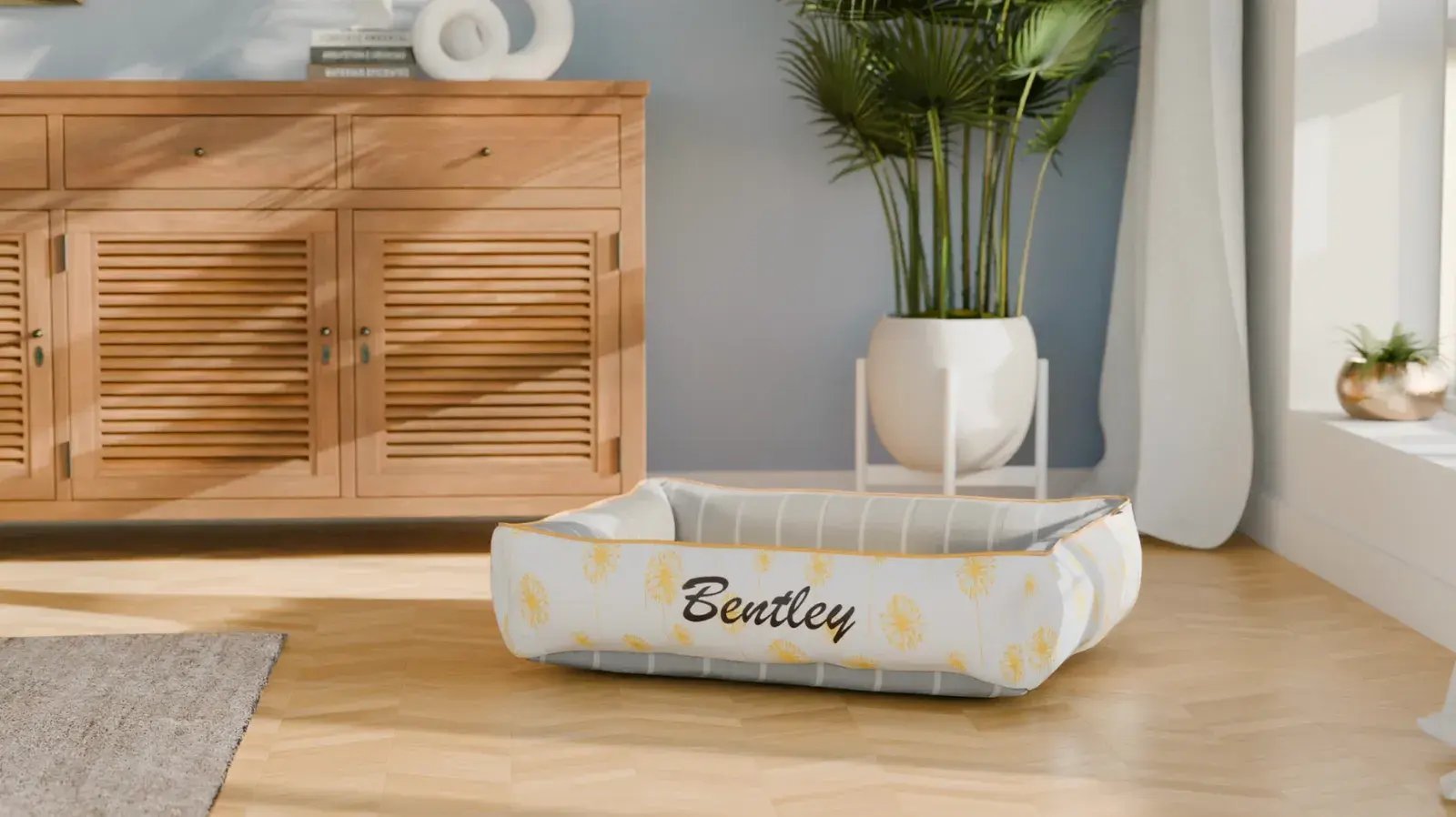 A Cozy Cuddle bed in yellow dandelion and grey stripe, embroidered Bentley, in a sunlit living room