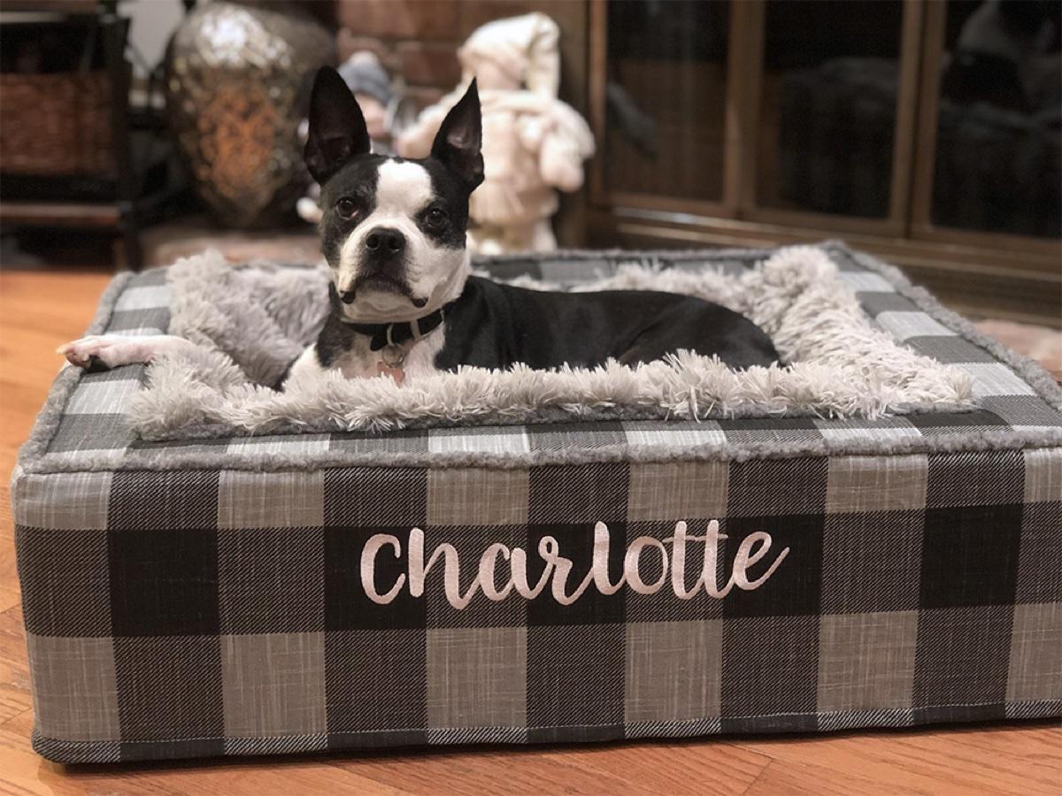 Throne dog bed with a gray plaid frame and attached fleece blanket